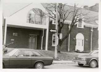Photo of library building and two cars parked outside on street. 
