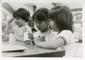 Photo of three children making puppets at table. 