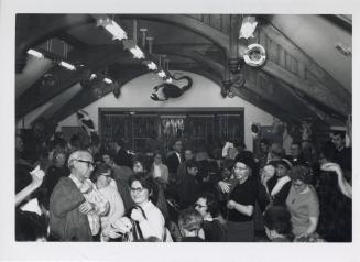 Photo of crowd of people standing inside large library room. 