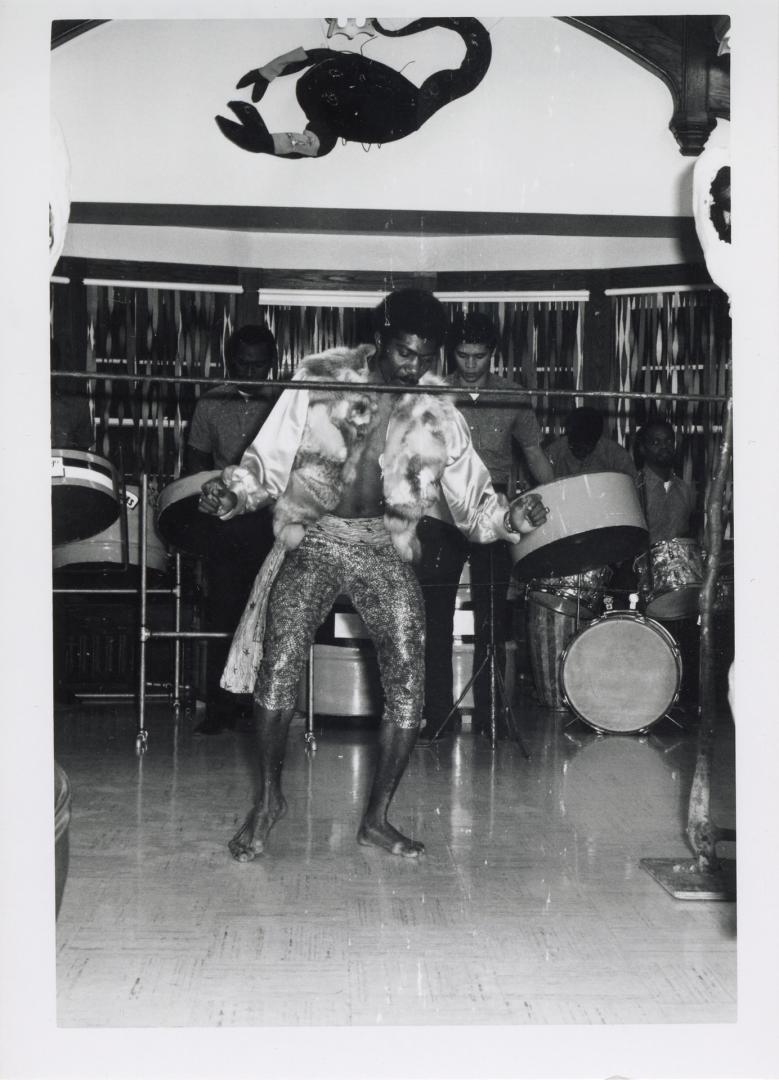 Photo of limbo dancer with steel band in background. 
