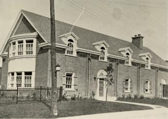 Photo of two storey library building with large bay windows at left end. 