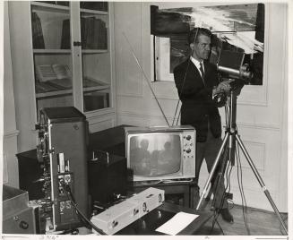 Photo of man videotaping with TV equipment in foreground. 