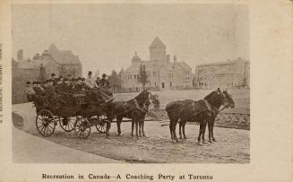 Large wagon full of people with four horses with large buildings in background. 