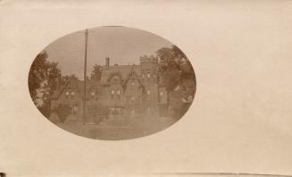 Sepia toned photograph of large mansion with gables and turrets.