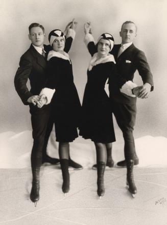 A photograph of four people on ice skates posing in a photography studio on what appears to be  ...