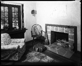 A photograph of the interior of a house. There is a fireplace with wood piled inside it on the  ...