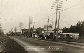 Sepia-toned photo postcard depicting Highway 2 looking east, with businesses on the right (sout ...