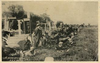 Sepia-toned photo postcard depicting men aiming their rifles outwards at an outdoor rifle range ...