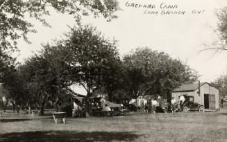 Black and white photo postcard depicting a tent and picnic tables in sight. A handwritten capti ...