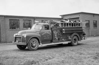 A photograph of a fire engine parked in front of a one store building. There is a ladder on the ...