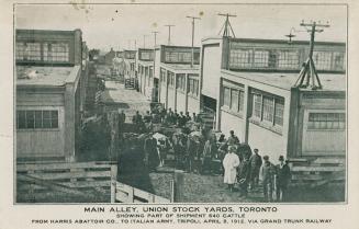 Black and white photograph of a group of men lined up outside of a row of factory buildings.