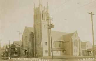 Black and white photograph of large stone church with streetcar track in front of it.