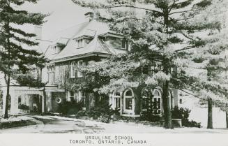 Black and white photograph of a large house with trees in front of it.
