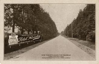 Black and white photo postcard depicting old Lakeshore Road, now Highway 2, with a big sign on  ...