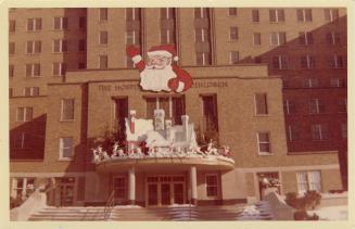 A photograph of the front entrance of a hospital, with Christmas decorations including a billbo ...