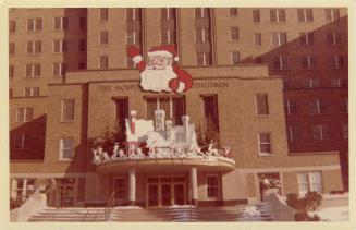 A photograph of the front entrance of a hospital, with Christmas decorations including a billbo…