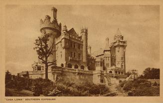 Sepia toned photograph of a castle with a stone wall in front of it.