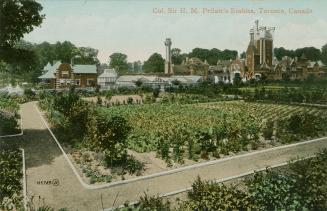 Colorized photograph of a garden with opulent outbuildings behind it.