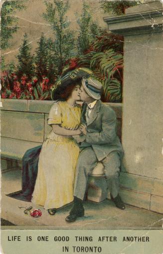 A man and woman kissing on a seat in a park.