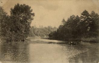 Sepia tone photograph of people sitting in a boat on a meandering river.