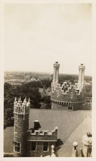 A photograph of a stone castle-like building, taken from a high vantage point on top of part of ...