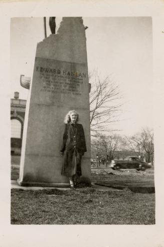 A photograph of a person standing in front of a monument with the words "EDWARD HANLAN" etched  ...