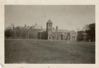 A photograph of a university campus, with a large stone building in the background and a large  ...