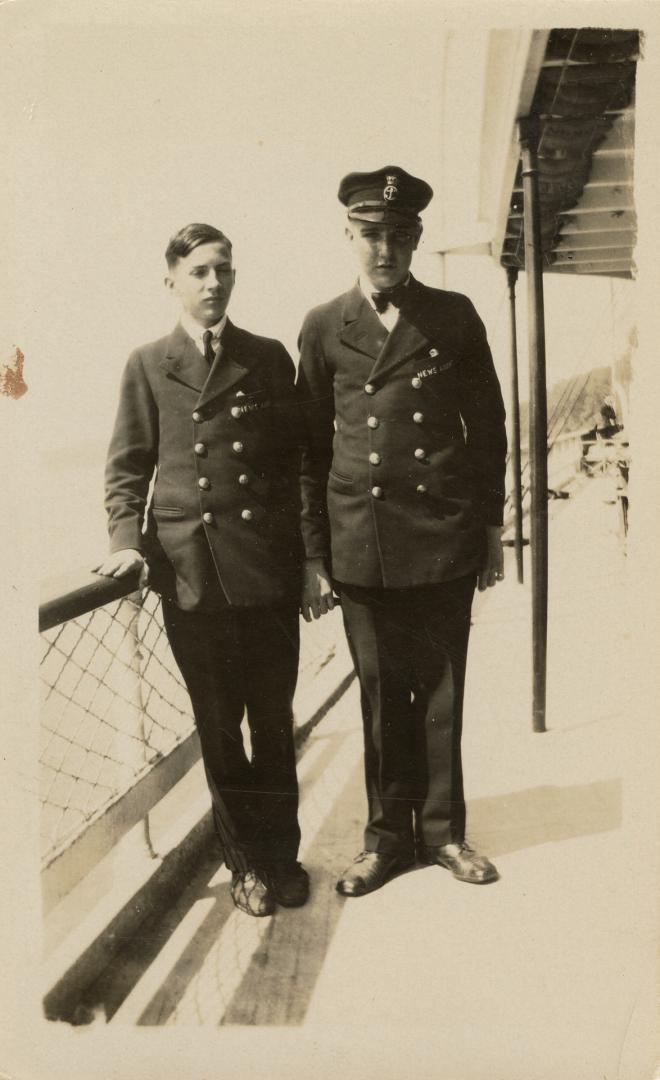 A photograph of two people standing on the deck of a ferry and wearing uniforms with two rows o ...