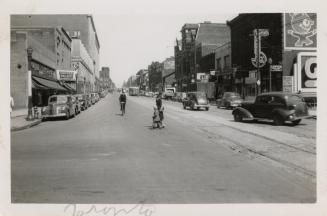 A photograph of a wide, paved city street with streetcar tracks in the middle of the street, ca ...