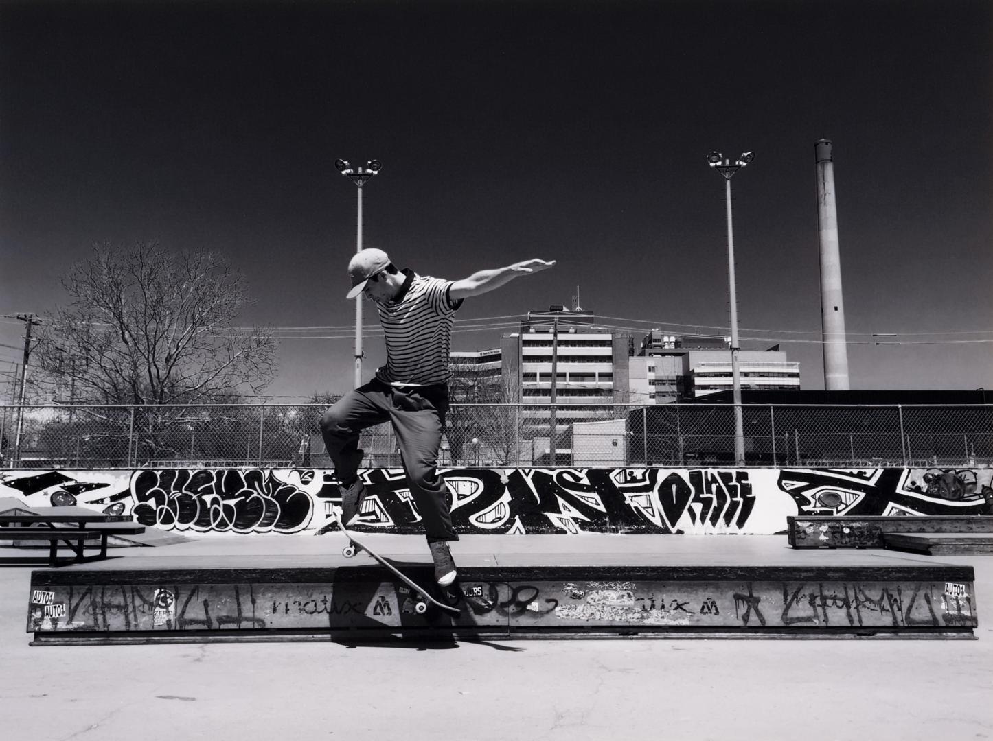 A photograph of a person skateboarding in a concrete skateboard park. The person is in midair, …