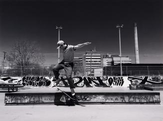 A photograph of a person skateboarding in a concrete skateboard park. The person is in midair,  ...