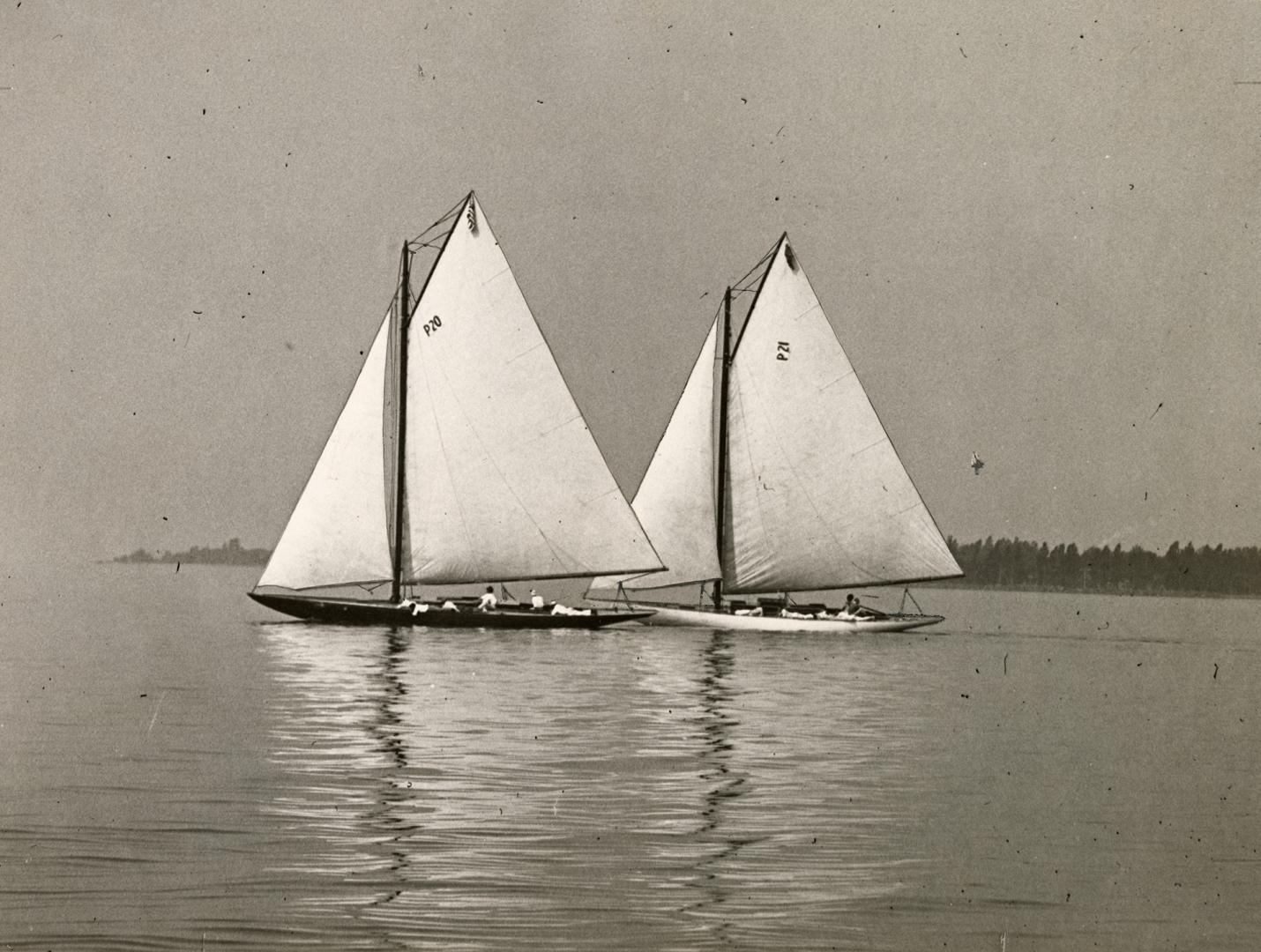 Black and white photograph of two sailboats in Toronto Harbour under full sail.