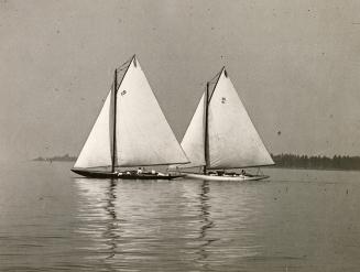 Black and white photograph of two sailboats in Toronto Harbour under full sail.