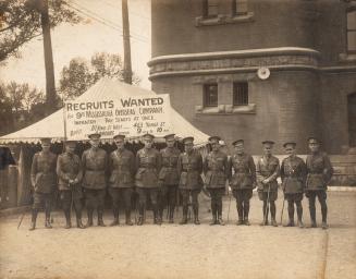 A photograph of a military recruiting tent in front of a large brick or stone building, located ...
