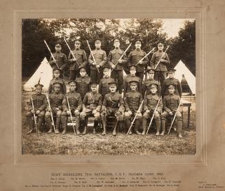 A photograph of a group of twenty men in military uniforms posing for a photograph in a grass f ...