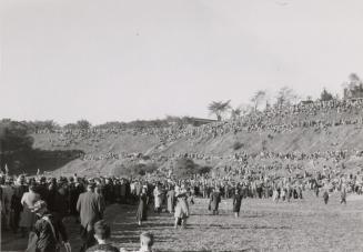 A photograph of a large crowd of people walking towards and gathered on a hillside surrounding  ...