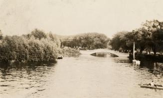 A photograph of a body of water separating wooded areas. There is a bridge spanning the water w ...