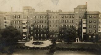 A photograph of a six story hospital, with a roundabout driveway in front of the building surro ...