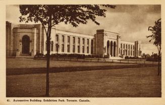 Sepia toned photograph of a two story building in the Beaux Arts style. Tall arches over the en…