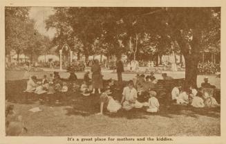 Sepia toned photograph of a crowd of people sitting on the lawn under shady trees.