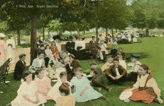 Colorized of a crowd of people, mostly children sitting on the grass in a park.