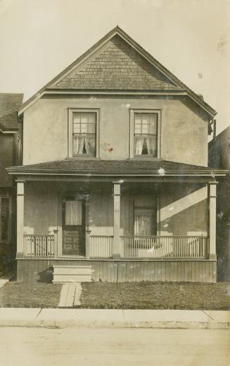 Black and white photograph of a two story house with a front verandah.