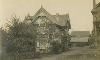 Black and white photograph of a large three story house and outbuildings.