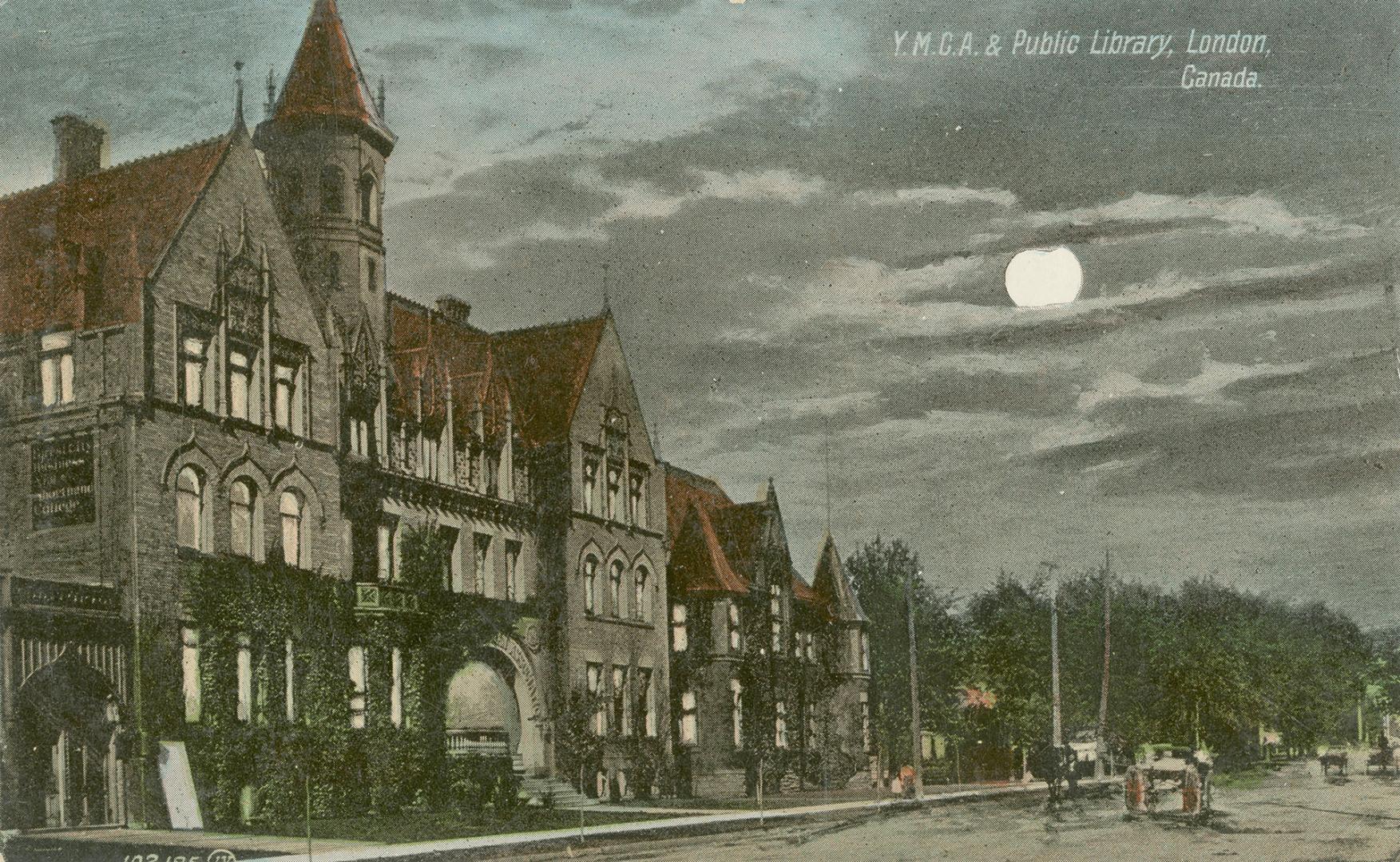 Picture of street at night with full moon and large buildings on one side of the street. 