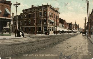 Colorized photograph of two and three story buildings on each side of a busy city street.