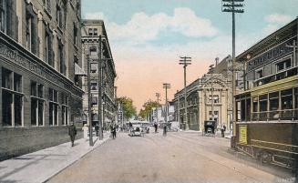 Colorized photograph of streetcars, automobiles and people traveling on a busy city street with ...