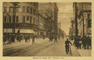 Sepia tones photograph of a very busy city street corner with automobiles and a streetcar. Poli ...