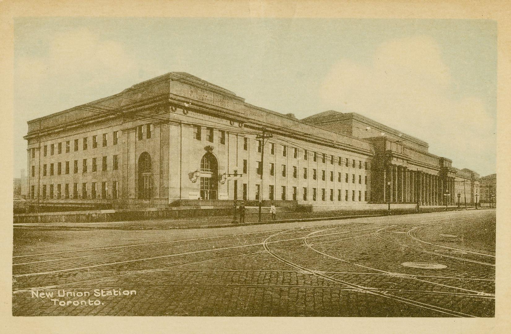 Colour photo postcard depicting Union station, bordered by cobblestone/brick-laid Front St. W.  ...
