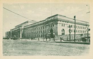 Green-toned photo postcard depicting Union station, bordered by an unpaved Front St. W. with pe ...