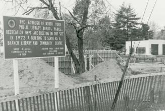 Construction site of library with large sign. 